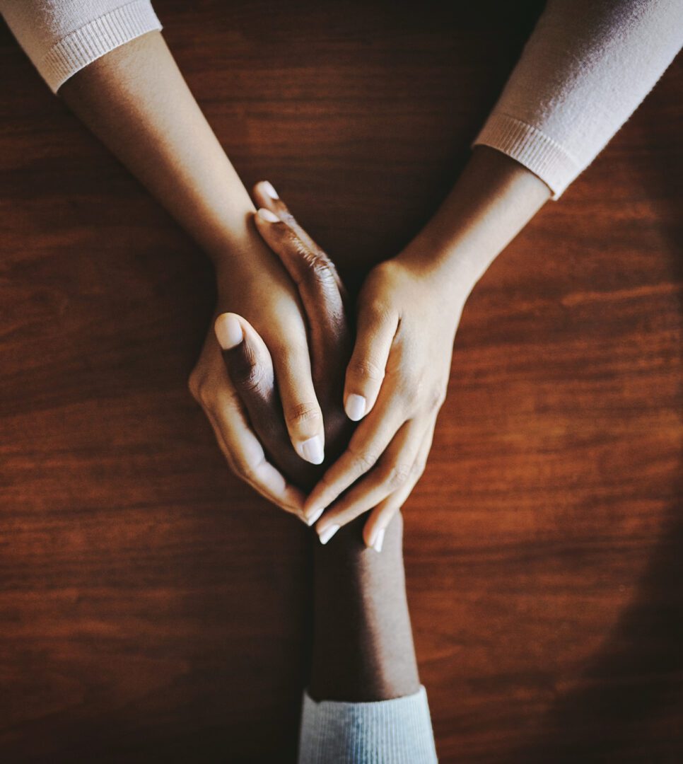 High angle shot of two people holding hands in comfort